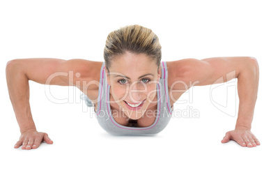 Strong woman doing press ups smiling at camera