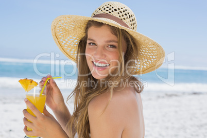 Pretty smiling blonde in bikini holding cocktail on the beach