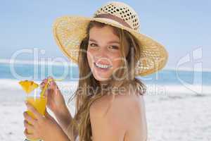 Pretty smiling blonde in bikini holding cocktail on the beach
