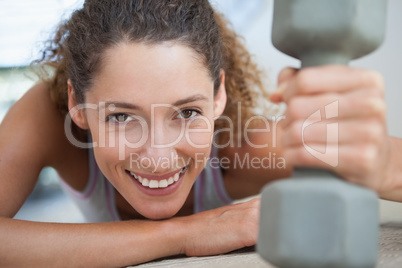 Fit woman smiling at camera holding dumbbell