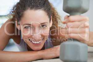 Fit woman smiling at camera holding dumbbell