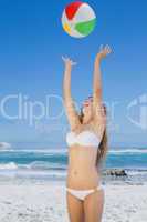 Smiling slim woman throwing beach ball