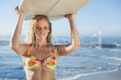 Gorgeous blonde surfer in bikini holding her board