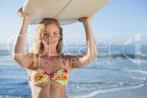 Gorgeous blonde surfer in bikini holding her board