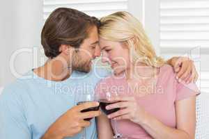 Happy couple drinking red wine together on the couch