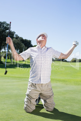 Kneeling golfer cheering on putting green