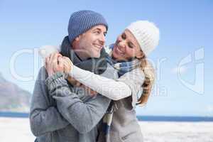 Attractive couple hugging on the beach in warm clothing