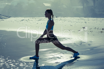 Fit woman doing lunges on the beach