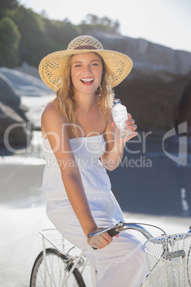 Beautiful blonde in sundress on bike holding water bottle at the