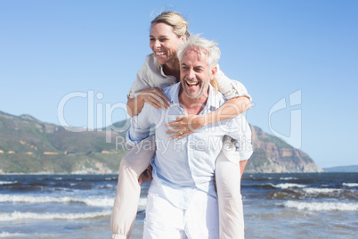 Man giving his laughing wife a piggy back at the beach Man giving his laughing wife a piggy back at the beach