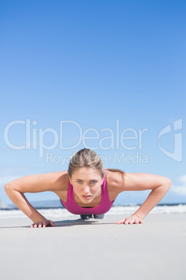 Fit blonde in plank position on the beach