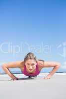 Fit blonde in plank position on the beach