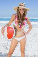 Fit smiling blonde in white bikini and straw hat holding beach b