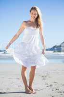 Woman in white dress smiling at camera on the beach