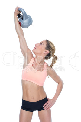 Female blonde crossfitter lifting kettlebell above head