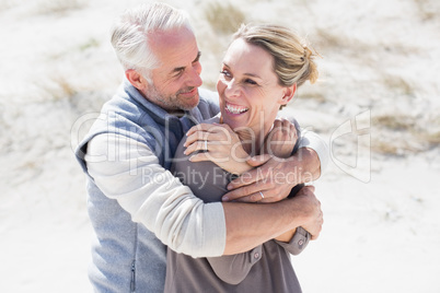 Happy hugging couple on the beach looking at each other