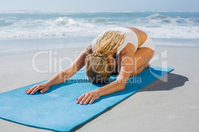 Gorgeous fit blonde in childs pose on the beach