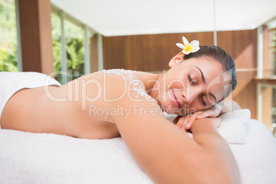 Beautiful brunette lying on massage table with salt scrub on bac