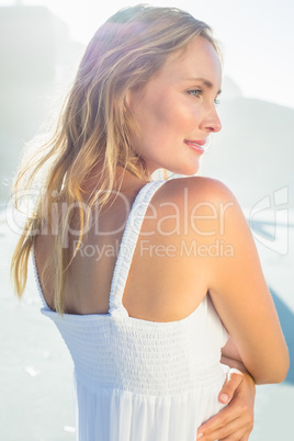 Pretty blonde standing at the beach in white sundress