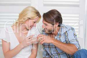 Cute young couple sitting on floor together having white wine