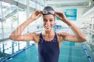 Pretty swimmer standing by the pool smiling at camera