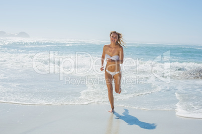 Gorgeous blonde in white bikini running from the sea