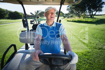 Happy golfer driving his golf buggy