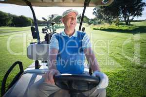 Happy golfer driving his golf buggy