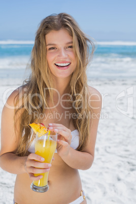 Pretty blonde in white bikini holding cocktail on the beach