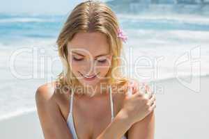 Beautiful blonde in white bikini smiling on the beach