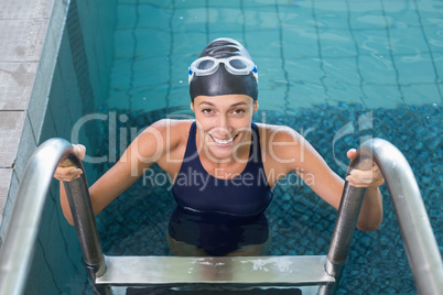 Fit swimmer smiling at camera getting out of the swimming pool
