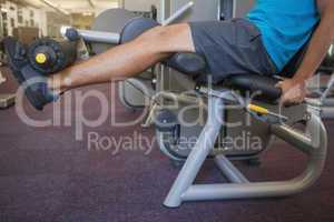Focused man using weights machine for legs