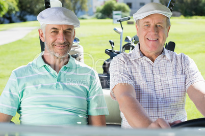 Golfing friends driving in their golf buggy smiling at camera