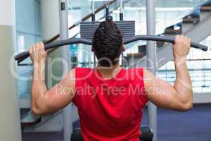 Strong bodybuilder using weight machine for arms