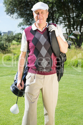 Golfer carrying his golf bag smiling at camera