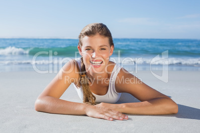 Sporty blonde lying on the beach smiling at camera