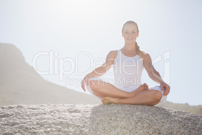 Smiling woman sitting in lotus pose on beach