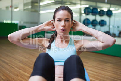 Fit brunette doing sit ups in fitness studio