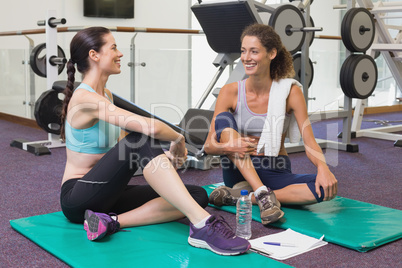 Fit friends chatting together on exercise mats