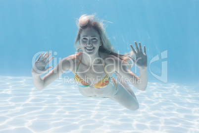 Cute blonde smiling at camera underwater in the swimming pool