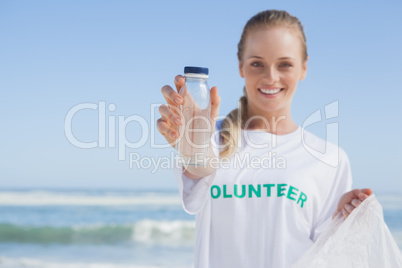 Blonde smiling volunteer picking up trash on the beach