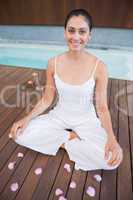 Peaceful brunette in white sitting in lotus pose surrounded by p