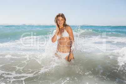 Beautiful smiling woman in white bikini standing in the sea