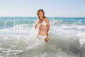 Beautiful smiling woman in white bikini standing in the sea