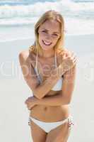 Beautiful blonde in white bikini smiling at camera on the beach