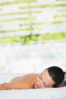 Smiling brunette lying on massage table with eyes closed