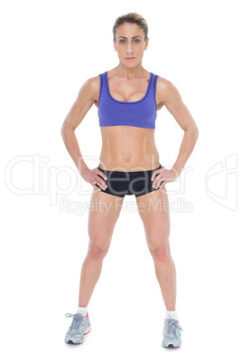Strong blonde posing with hands on hips looking at camera