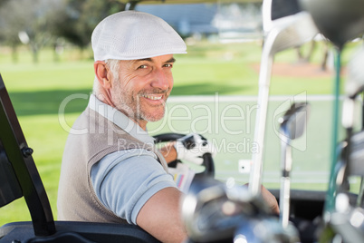 Happy golfer driving his golf buggy smiling at camera