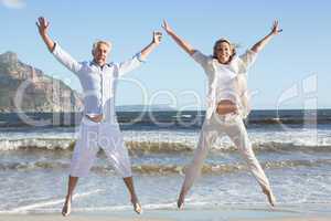 Happy couple jumping on the beach together