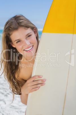 Pretty surfer girl holding her surfboard on the beach